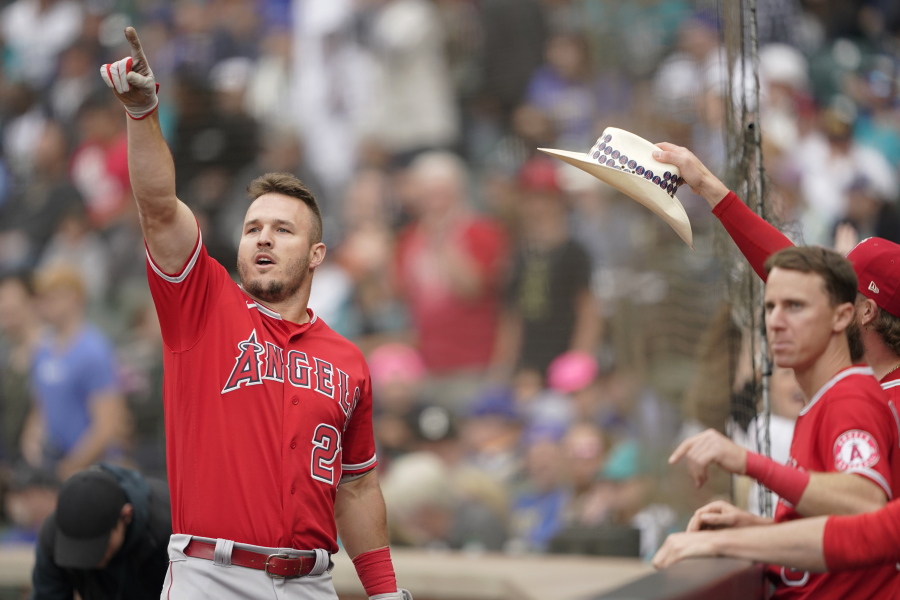 Los Angeles Angels' Mike Trout, left, points toward the outfield as he is greeted at the dugout after hitting a two-run home run in the tenth inning of the first baseball game of a doubleheader against the Seattle Mariners, Saturday, June 18, 2022, in Seattle. The Angels won 4-2 in ten innings. (AP Photo/Ted S.