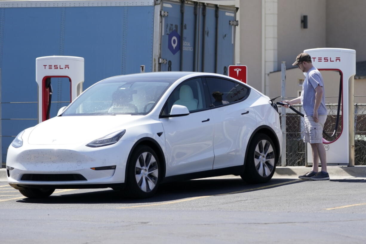 FILE - A Tesla owner charges his vehicle at a charging station in Topeka, Kan., Monday, April 5, 2021.  Tesla reported 273 crashes involving partially automated driving systems, according to statistics released by U.S. safety regulators on Wednesday, June 15, 2022. But the National Highway Traffic Safety Administration cautioned against using the numbers to compare automakers, saying it didn't weigh them by the number of vehicles from each manufacturer that use the systems, or how many miles those vehicles traveled.