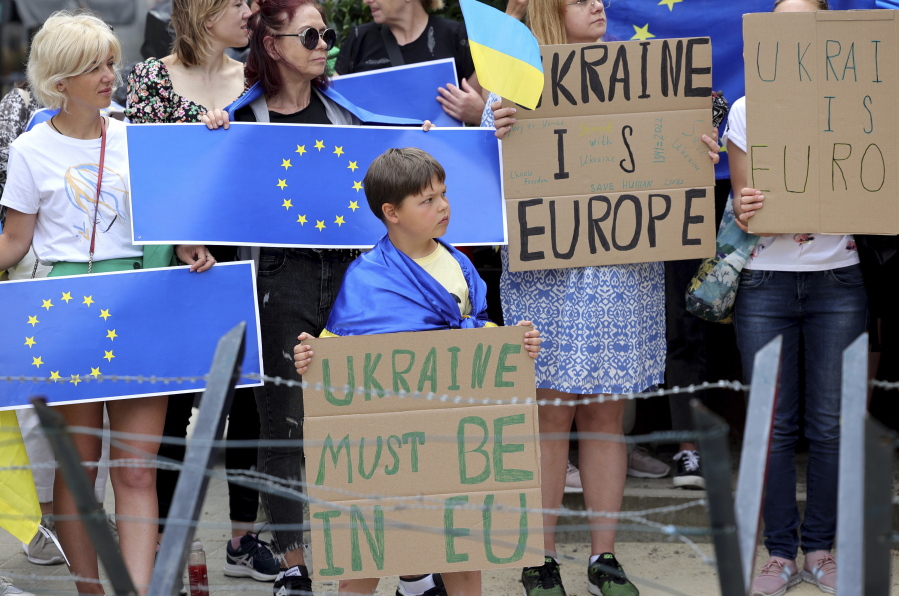 Protestors in support of Ukraine stand with signs and EU flags during a demonstration outside of an EU summit in Brussels, Thursday, June 23, 2022. European Union leaders are expected to approve Thursday a proposal to grant Ukraine a EU candidate status, a first step on the long toward membership.