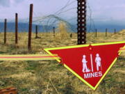 FILE - An international sign warning about mines hangs beside a minefield at Bagram Air Base on, March 22, 2002. The White House announced Tuesday a new policy curtailing the use of anti-personnel land mines by the U.S. military, reversing a more permissive stance that was enacted by former President Donald Trump. Under the policy, such explosives will still be allowed to defend South Korea against a potential attack by North Korea, but otherwise they will be banned.