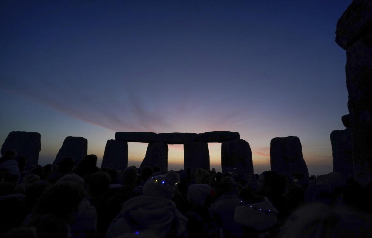 Dawn breaks behind the stones during the Summer Solstice festivities at Stonehenge in Wiltshire, England, Tuesday, June 21, 2022. After two years of closure due to the COVID-19 pandemic, Stonehenge reopened Monday for the Summer Solstice celebrations.