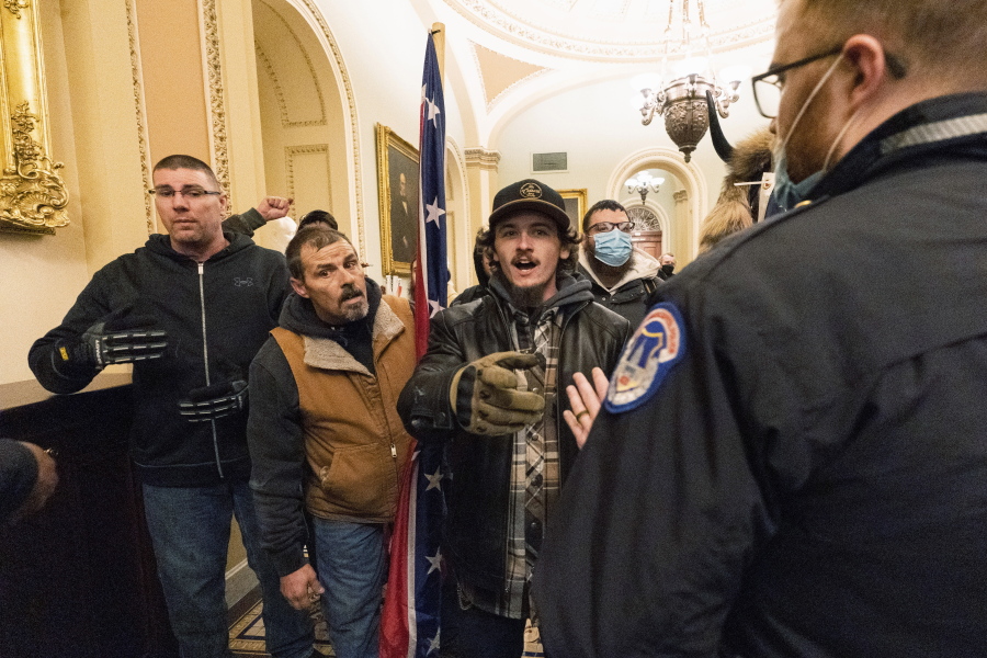 FILE - Kevin Seefried, second from left, holds a Confederate battle flag as he and other insurrectionists loyal to President Donald Trump are confronted by U.S. Capitol Police officers outside the Senate Chamber inside the Capitol in Washington, Jan. 6, 2021. A federal judge on Wednesday, June 15, 2022, convicted Kevin Seefried and his adult son Hunter Seefried of charges that they stormed the U.S. Capitol together to obstruct Congress from certifying President Joe Biden's 2020 electoral victory.
