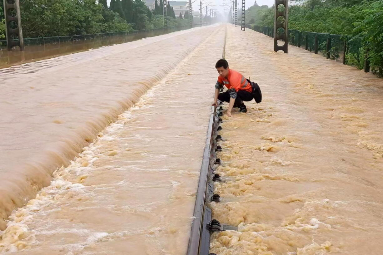 A worker checks a section of flooded railway in Shangrao in central China's Jiangxi province, Tuesday, June 21, 2022. Major flooding has forced the evacuation of tens of thousands of people in southern China, with more rain expected.