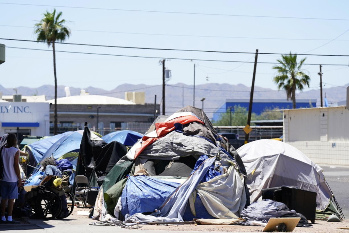 A homeless encampment grows in size just west of downtown Friday, May 20, 2022, in Phoenix. Hundreds of homeless people die in the streets each year from the heat, in cities around the U.S. and the world. The ranks of homeless have swelled after the pandemic and temperatures fueled by climate change soar. (AP Photo/Ross D.