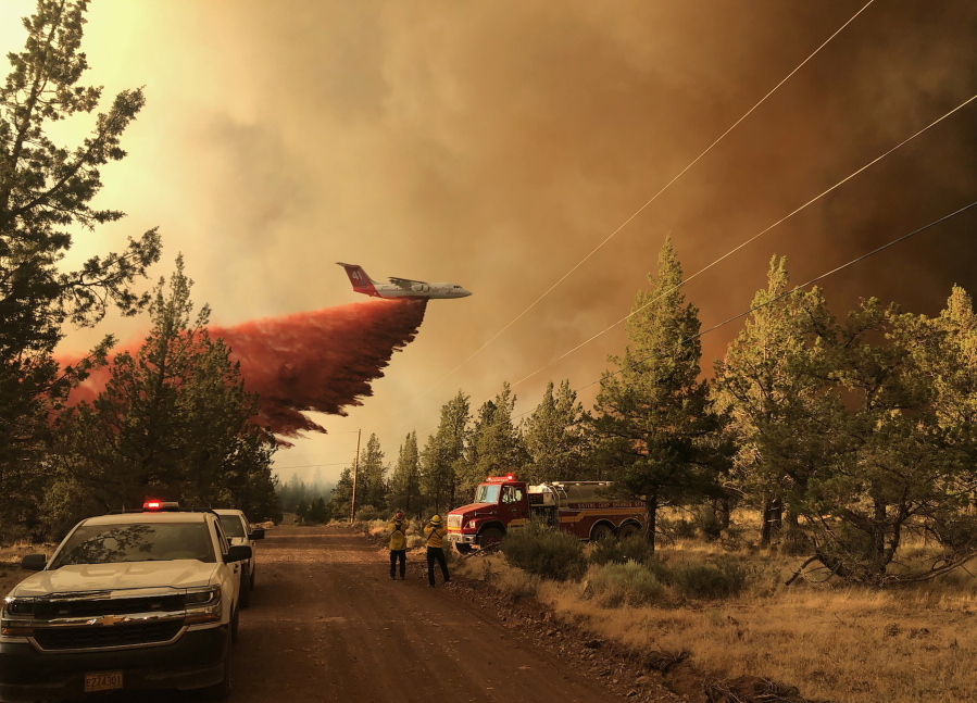FILE - This photo provided by the Oregon Department of Forestry shows a firefighting tanker making a retardant drop over the Grandview Fire near Sisters, Ore., Sunday, July 11, 2021. The wildfire doubled in size to 6.2 square miles (16 square kilometers) Monday, forcing evacuations in the area, while the state's biggest fire continued to burn out of control, with containment not expected until November.