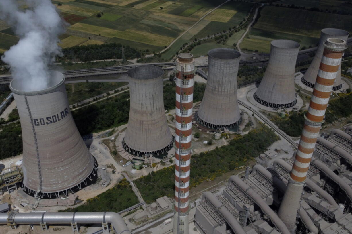 Steam rises from a cooling tower at the Agios Dimitrios power plant of Public Power Company (PPC) outside the northern city of Kozani on Friday, June 3, 2022. The phrase "Go Solar" was written years ago by Greenpeace activists.