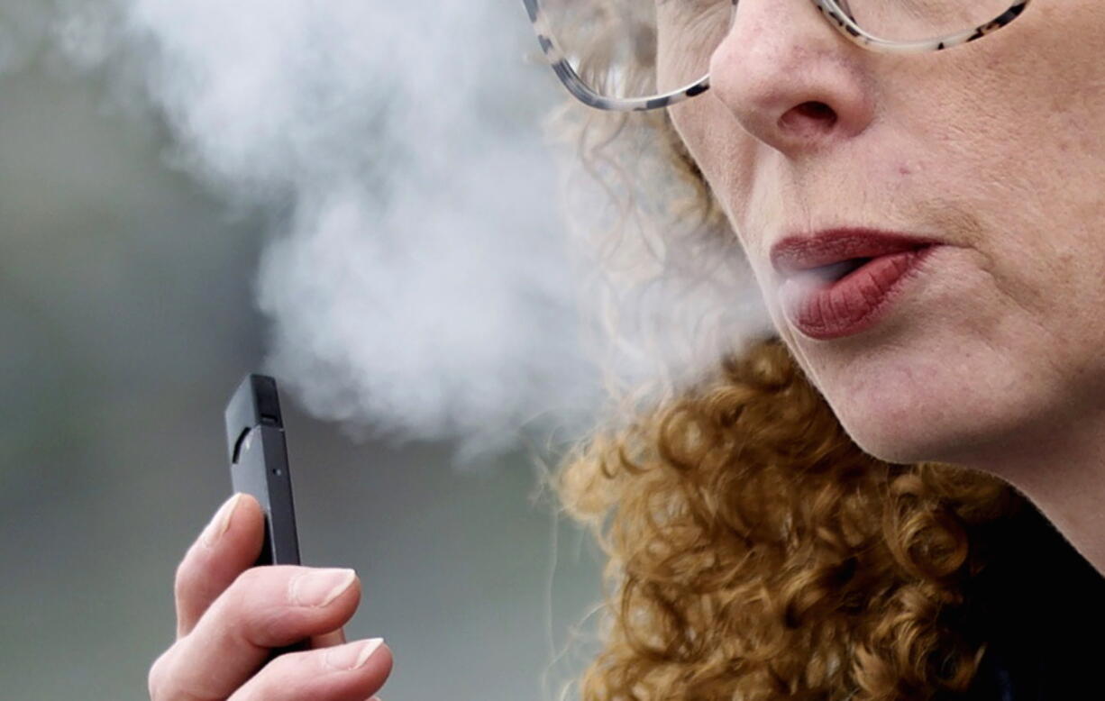 FILE -- A woman exhales while vaping from a Juul pen e-cigarette in Vancouver, Wash., April 16, 2019. Juul has asked a federal court, Friday, June 24, 2022, to block a government order to stop selling its electronic cigarettes. Federal health officials on Thursday, June 23,  ordered Juul to pull its electronic cigarettes from the U.S. market, the latest blow to the embattled company widely blamed for sparking a national surge in teen vaping.