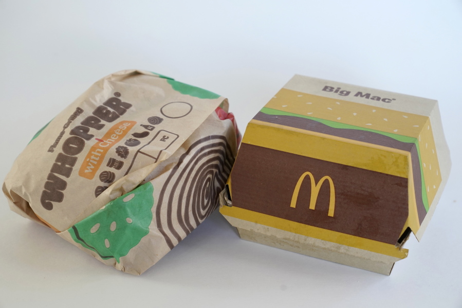 A Burger King Whopper in a wrapper, left, rests next to a McDonald's Big Mac in a container, in Walpole, Mass., Wednesday, April 20, 2022. Environmental and health groups are pushing dozens of fast food companies, supermarket chains and other retail outlets to remove PFAS from their packaging.