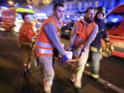FILE - A woman is evacuated from the Bataclan concert hall after a shooting on Nov. 13, 2015 in Paris. The historic trial in Paris of 20 men suspected of critical roles in the Islamic State massacres that killed 130 people in 2015 has ended this week with verdicts against the defendants in France's worst peacetime attack expected on Wednesday June 29.