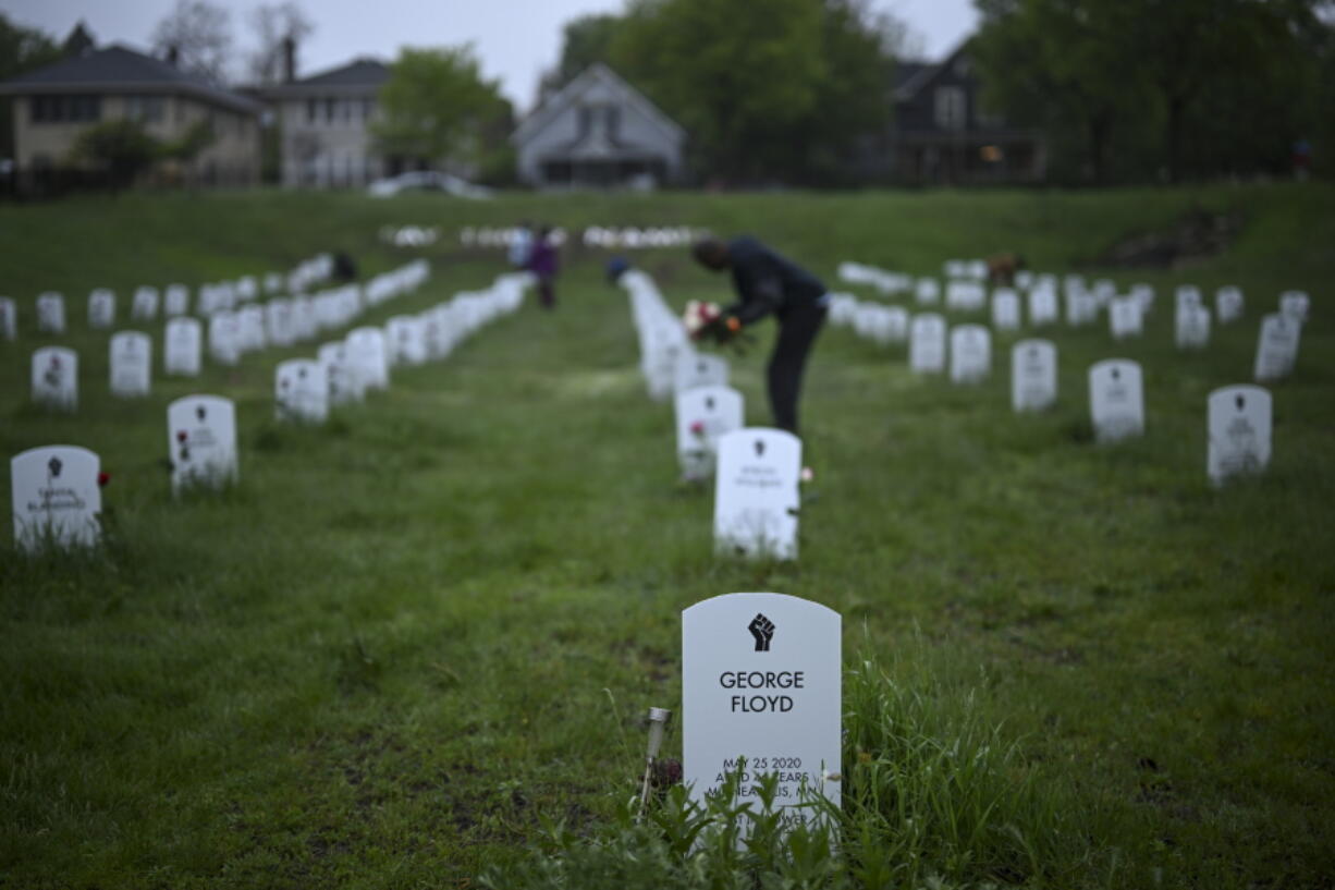 Community members lay flowers down near gravestone markers at the 'Say Their Names' cemetery Wednesday, May 25, 2022, in Minneapolis. The intersection where George Floyd died at the hands of Minneapolis police officers was renamed in his honor Wednesday, among a series of events to remember a man whose killing forced America to confront racial injustice.