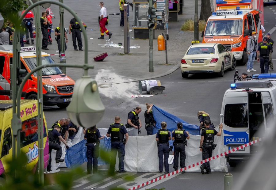 Police officers cover a dead body after a car crashed into a crowd of people in central Berlin, Germany, Wednesday, June 8, 2022.