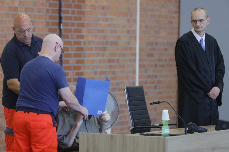 The accused Josef S. covers his face as he sits at the court room in Brandenburg, Germany, Tuesday, June 28, 2022. A 101-year-old man has been convicted of 3,518 counts of accessory to murder for serving at the Nazis' Sachsenhausen concentration camp during World War II. The Neuruppin Regional Court sentenced him to five years in prison on Tuesday.