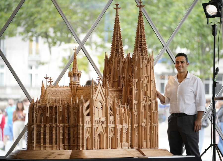 Fadel Alkhudr from Syria poses beside his wooden model of the word heritage Cologne Cathedral on display at the Domforum in Cologne, Germany, Monday, June 20, 2022. Fadel Alkhudr, 42, a woodcarver and artist orginally from Aleppo, Syria, fled the war in his home country and arrived in the western german city of Cologne in 2015. In 2019 he started to carve the local Cologne Cathedral in his small basement - without any plans or drawings, using only cell phone photos of the cathedral as a template.