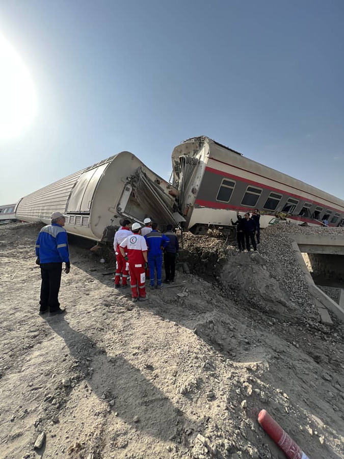 In this photo provided by Iranian Red Crescent Society, rescuers work at the scene where a passenger train partially derailed near the desert city of Tabas in eastern Iran, Wednesday, June 8, 2022.