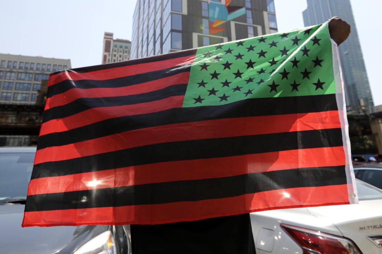 FILE - A man holds an African-American flag during a demonstration in Chicago on June 19, 2020, to mark Juneteenth, the holiday celebrating the day in 1865 that enslaved black people in Galveston, Texas, learned they had been freed from bondage, more than two years after the Emancipation Proclamation. Retailers and marketers from Walmart to Amazon have been quick to commemorate Juneteenth with an avalanche of merchandise from ice cream to T-shirts to party favors. (AP Photo/Nam Y.