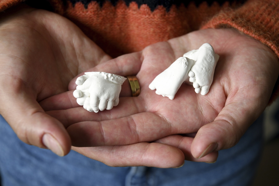 Christina Taylor holds plaster casts of her baby's hands and feet at her home in Littleton, Colo., on Wednesday, April 27, 2022. Taylor chose to get an abortion when she found out after 20 weeks that her baby had no kidneys or bladder. Taylor said she honors her loss with the casts, which were made by the hospital's bereavement team.