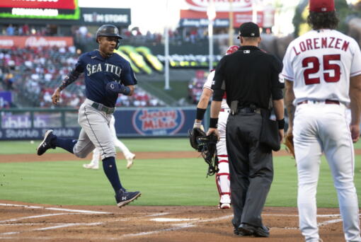 Seattle Mariners Julio Rodriguez, left, scores on a single by Eugenio Suarez as Los Angeles Angels starting pitcher Michael Lorenzen, right, watches along with home plate umpire Will Little during the first inning of a baseball game Friday, June 24, 2022, in Anaheim, Calif. (AP Photo/Mark J.