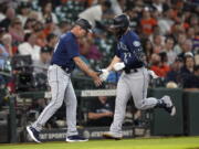 Seattle Mariners' Ty France (23) celebrates with third base coach Manny Acta after hitting a home run against the Houston Astros during the fourth inning of a baseball game Wednesday, June 8, 2022, in Houston. (AP Photo/David J.