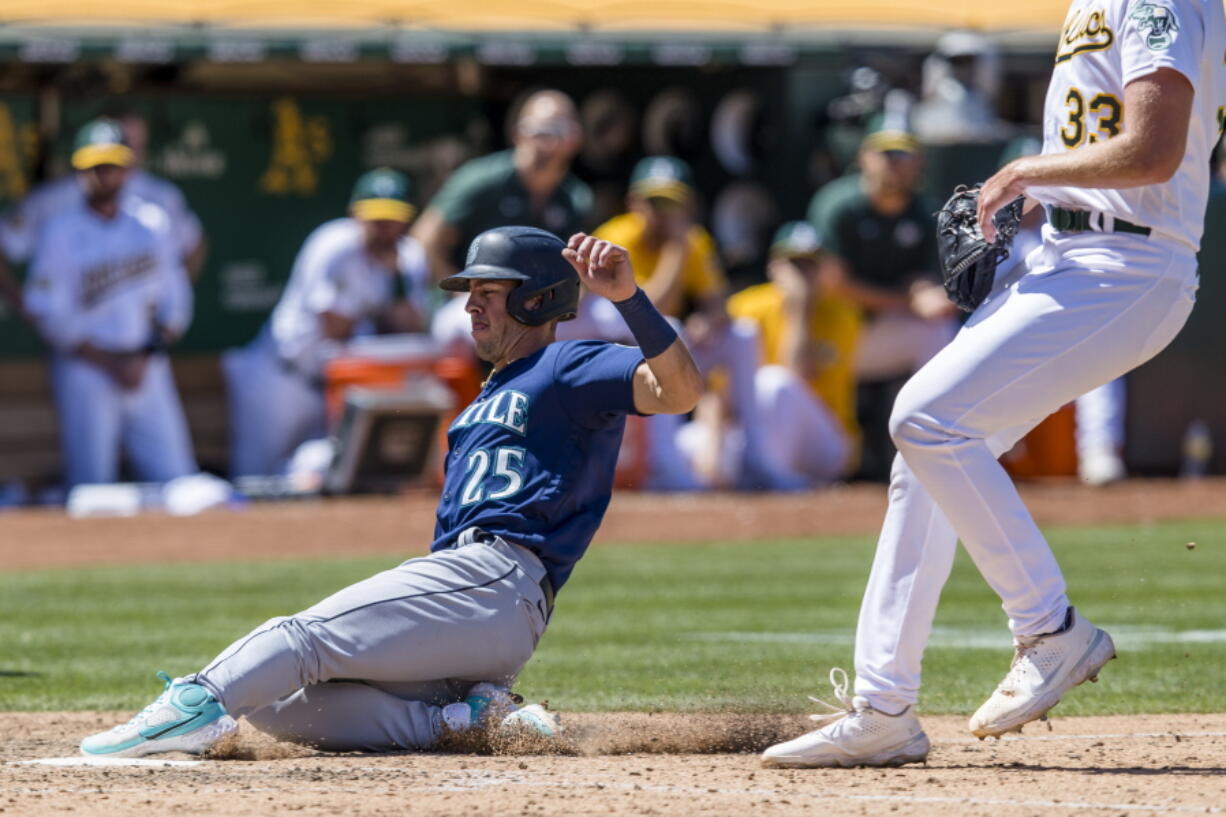 Seattle Mariners' Dylan Moore (25) scores on a wild pitch by Oakland Athletics' A.J. Puk (33) during the ninth inning of a baseball game in Oakland, Calif., Thursday, June 23, 2022.