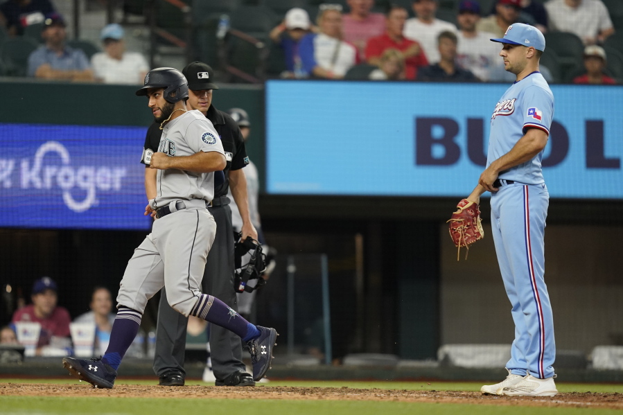 Seattle Mariners's Abraham Toro, left, scores in front of Texas Rangers pitcher Brock Burke, right, after a wild pitch during the 10th inning of a baseball game in Arlington, Texas, Sunday, June 5, 2022.