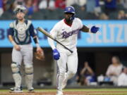Texas Rangers' Adolis Garcia, right, tosses his bat in front of Seattle Mariners catcher Cal Raleigh, left, after hitting a three-run home run during the fourth inning of a baseball game in Arlington, Texas, Saturday, June 4, 2022. Rangers' Marcus Semien and Mitch Garver also scored on the play.
