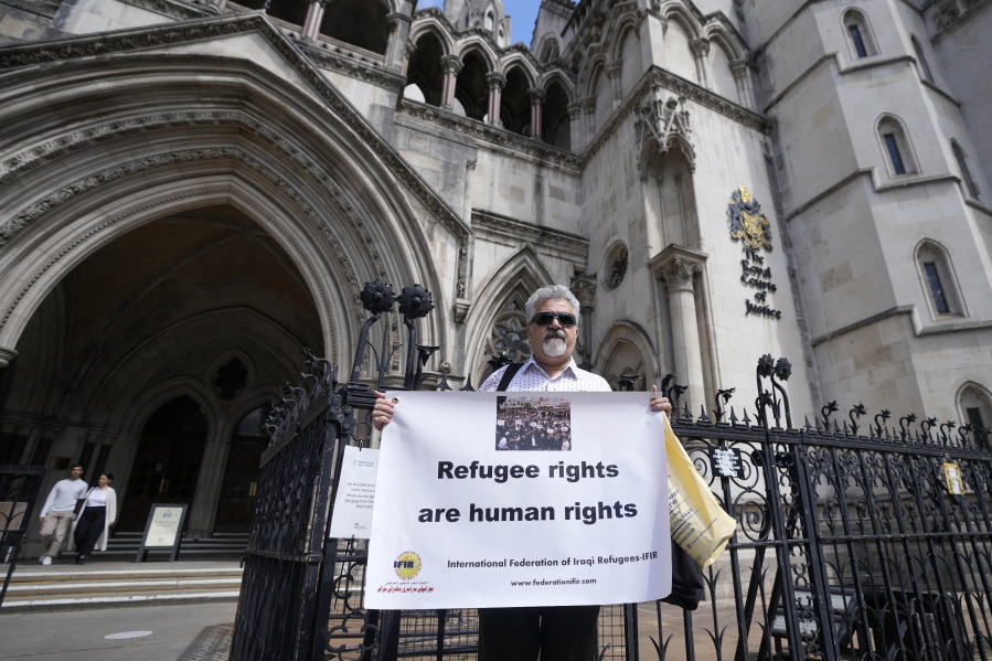 Protestors stand outside The Royal Court of Justice in London, Friday, June 10, 2022. The High Court will hear a legal challenge lodged by Care4Calais, the Public and Commercial Services Union (PCS) and Detention Action, opposing the Home Office's new asylum deal with Rwanda. The case alleges that Priti Patel's proposals are in contravention of international law and the UN refugee convention.