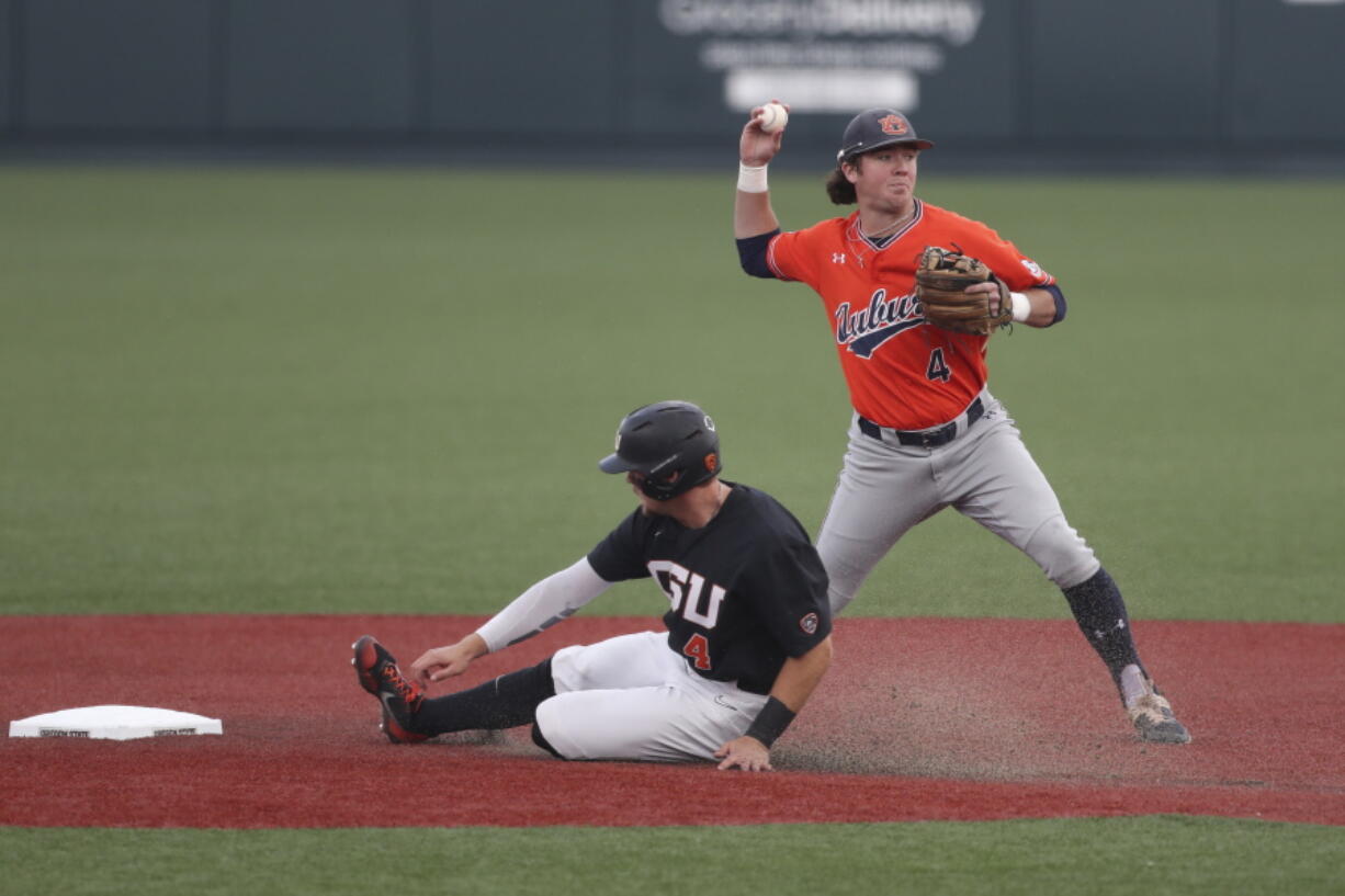 Auburn infielder Brody Moore, right, throws to first base after putting out Oregon State's Justin Boyd, left, during the first inning on Monday in Corvallis, Ore.