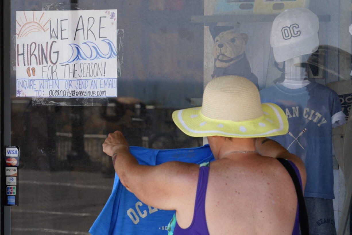 A hiring sign is seen as a person shops for souvenirs along the boardwalk, Thursday, June 2, 2022, in Ocean City, N.J. It's a hot job market right now, and that extends to the youngest workers. The unemployment rate for teenagers ages 16-19 was just over 10% in April. Given the strife and isolation of the past couple of years, it's teens who may have the most to gain by going to work this summer.
