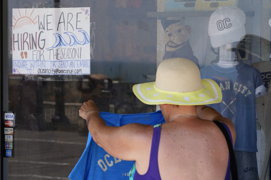 A hiring sign is seen as a person shops for souvenirs along the boardwalk, Thursday, June 2, 2022, in Ocean City, N.J. It's a hot job market right now, and that extends to the youngest workers. The unemployment rate for teenagers ages 16-19 was just over 10% in April. Given the strife and isolation of the past couple of years, it's teens who may have the most to gain by going to work this summer.