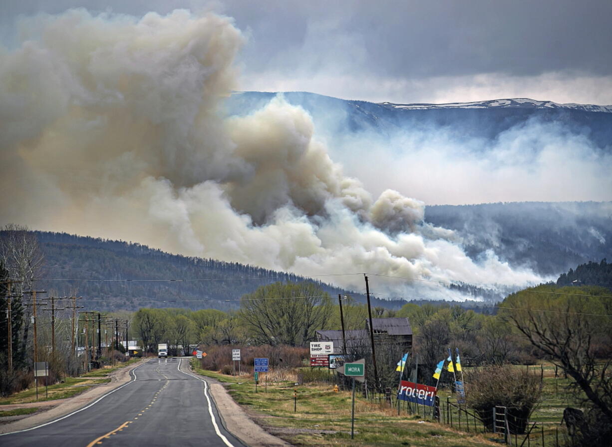 FILE - A flare up near Cleveland, just down 519 from Mora, N.M., darkens the sky on Wednesday, May 4, 2022, where firefighters have been battling the Hermit's Peak and Calf Canyon fire for weeks. New Mexico residents are suing the U.S. Forest Service for information on a massive wildfire that's been burning in the state since late April. The agency has been criticized for its role in causing two wildfires that merged to become the largest blaze in New Mexico history.