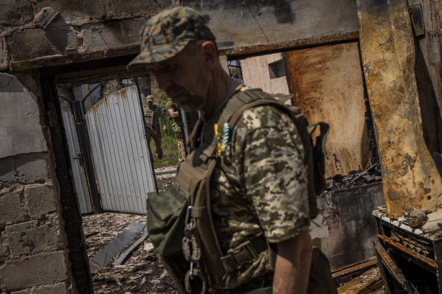 FILE - Commander of an artillery unit of the Ukrainian army, Mykhailo Strebizh, center, inside a destroyed house due to shelling in a village near the frontline in the Donetsk oblast region, eastern Ukraine, Thursday, June 2, 2022.