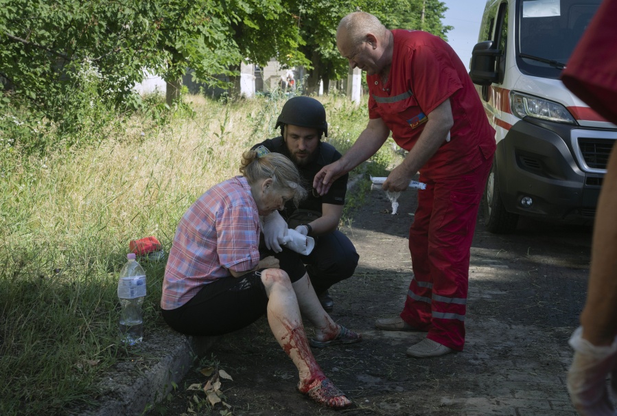 A police officer and paramedic give the first aid to a woman wounded by the Russian shelling in city center in Slavyansk, Donetsk region, Ukraine, Monday, June 27, 2022.