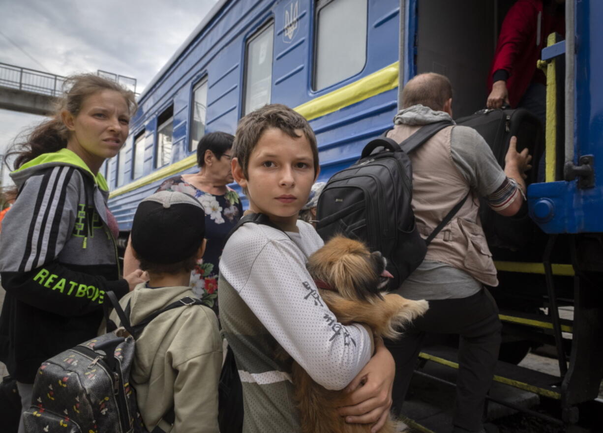 A boy holds his pet dog as his family evacuated from the war-hit area gets on an evacuation train in Pokrovsk, eastern Ukraine, Saturday , June 25, 2022.