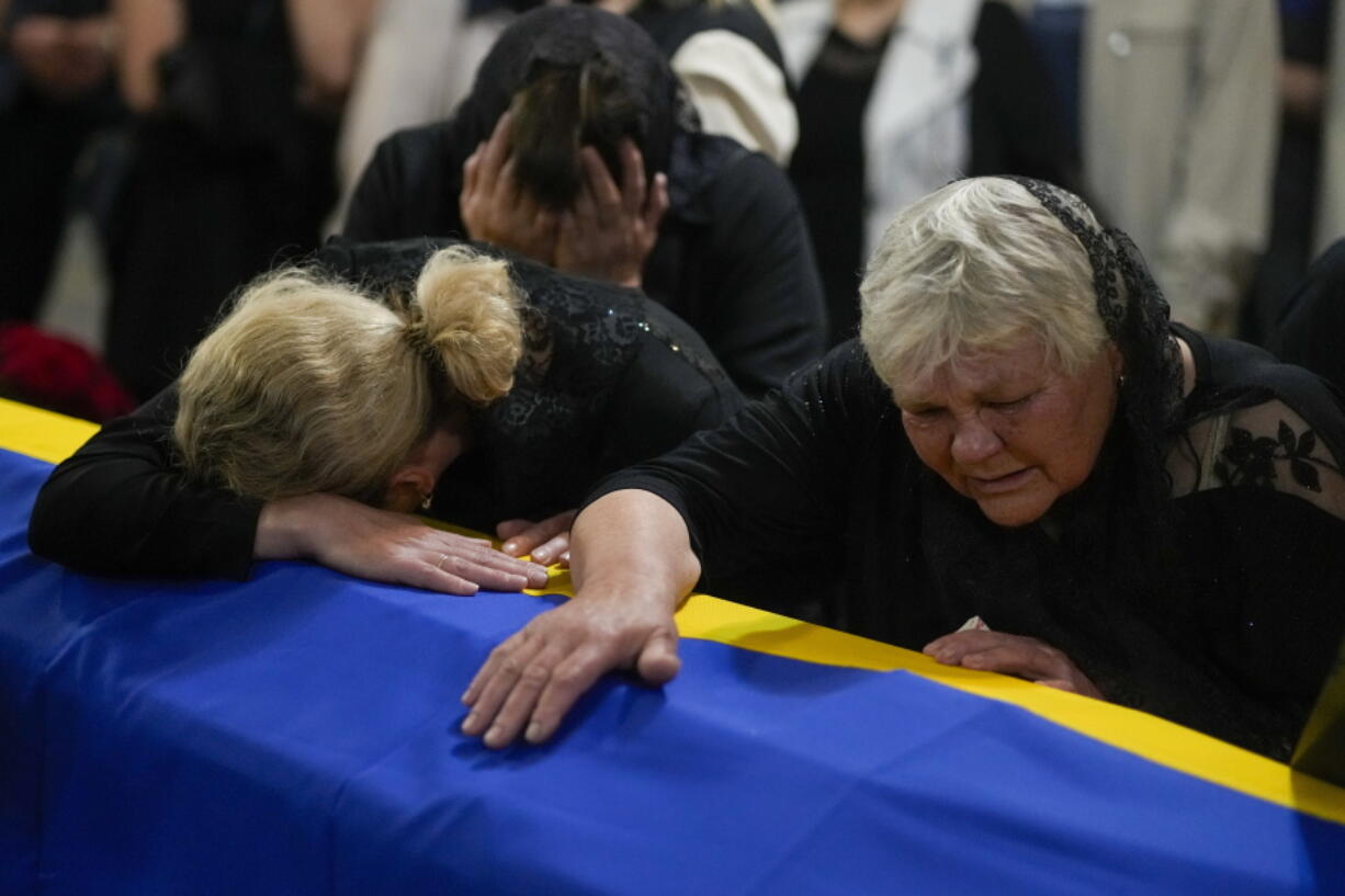 The mother, right, and sister of Army Col. Oleksander Makhachek mourn over the coffin with his remains during a funeral service in Zhytomyr, Ukraine, Friday, June 3, 2022. According to combat comrades Makhachek was killed fighting Russian forces when a shell landed in his position on May 30.