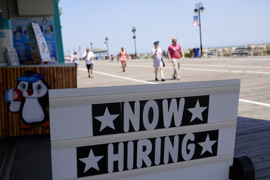 A now hiring sign is seen in front of a business along the boardwalk, Thursday, June 2, 2022, in Ocean City, N.J. Many seasonal businesses are struggling to find enough workers again this summer.