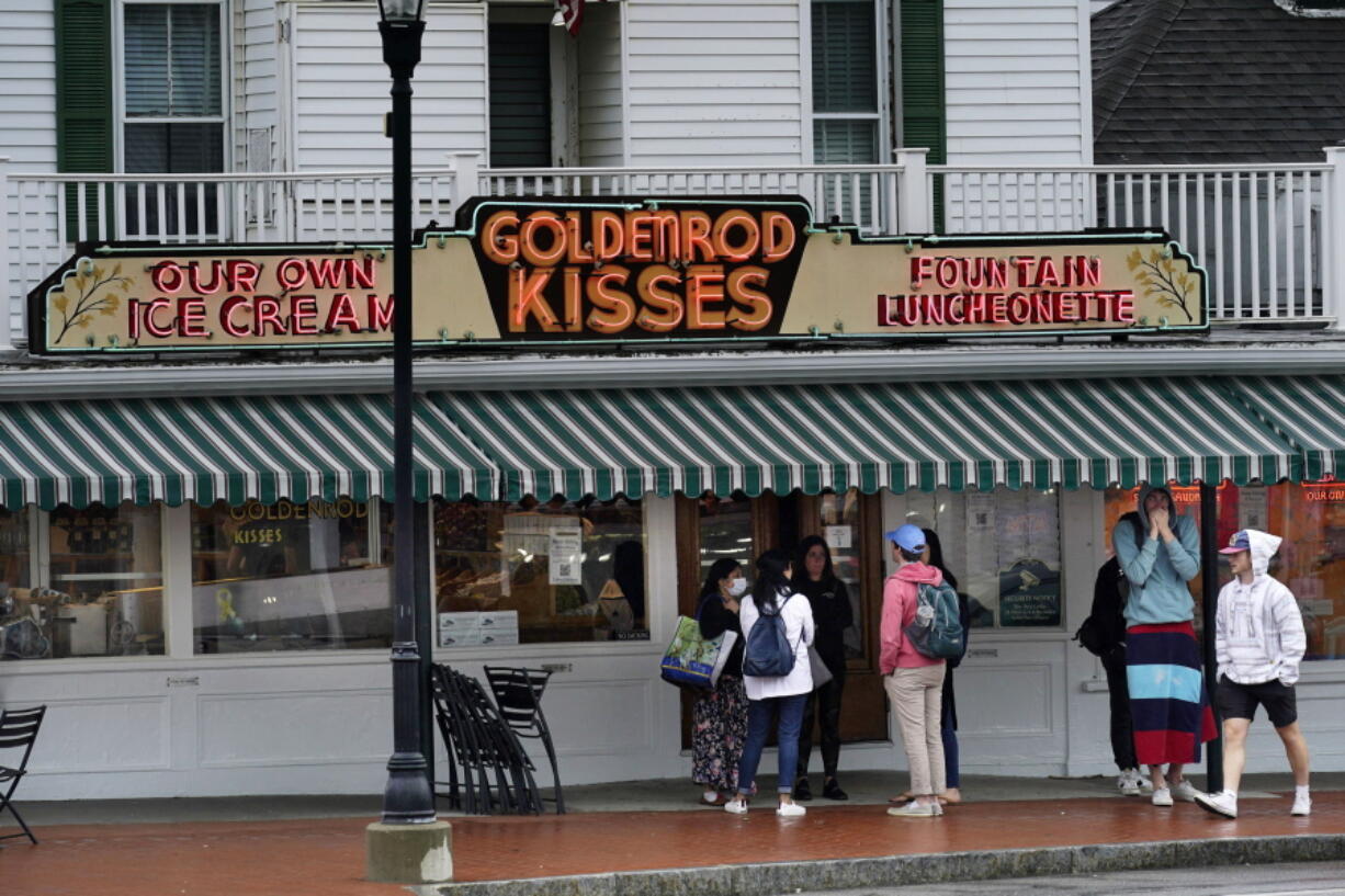 High school students gather outside The Goldenrod, a popular restaurant and candy shop, Wednesday, June 1, 2022, in York Beach, Maine. Many seasonal businesses are struggling to find enough workers agin this summer. (AP Photo/Robert F.