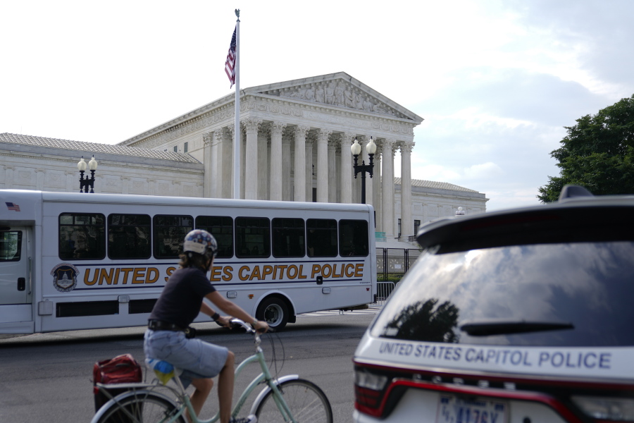 A bicyclist rides past police vehicles parked outside the U.S. Supreme Court building, Monday, June 27, 2022, in Washington.