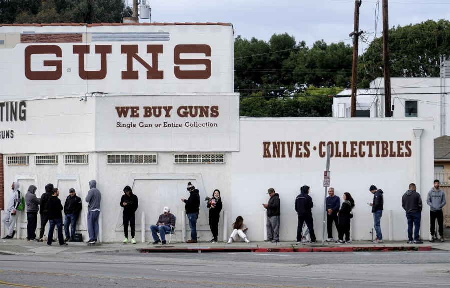 FILE - In this March 15, 2020 file photo people wait in a line to enter a gun store in Culver City, Calif. The man who shot and killed four people this week at a Tulsa, Okla., hospital bought his AR-style semiautomatic rifle just hours before he began the killing spree. That would not have been possible in Washington and a half dozen other states that have waiting periods of days or even more than a week before people can take possession of such weapons. (AP Photo/Ringo H.W.