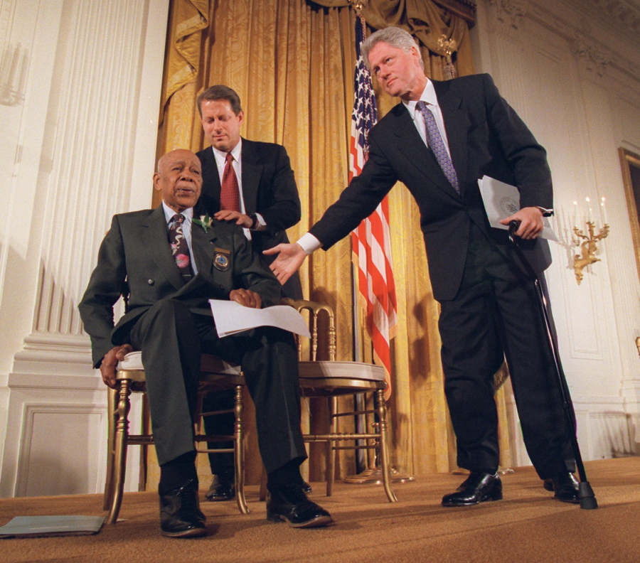 FILE - President Clinton and Vice President Al Gore, back, help Herman Shaw, 94, a Tuskegee Syphilis Study victim, during a news conference on May 16, 1997. Fifty years after the infamous Tuskegee syphilis study was revealed to the public in 1972 and halted, Manhattan-based philanthropy organization Milbank Memorial Fund is publicly apologizing for its role in the infamous Tuskegee syphilis study.