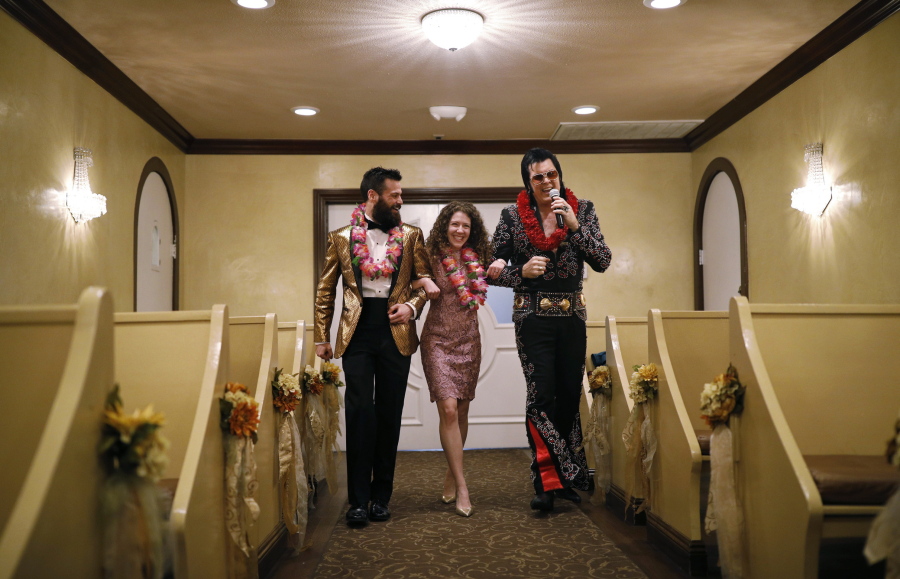 Elvis impersonator Brendan Paul, right, walks down the aisle during a wedding ceremony for Katie Salvatore, center, and Eric Wheeler at the Graceland Wedding Chapel in Las Vegas.