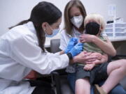 Pharmacist Kaitlin Harring, left, administers a Moderna COVID-19 vaccination to three year-old Fletcher Pack, while he sits on the lap of his mother, McKenzie Pack, at Walgreens pharmacy Monday, June 20, 2022, in Lexington, S.C. Today marked the first day COVID-19 vaccinations were made available to children under 5 in the United States.