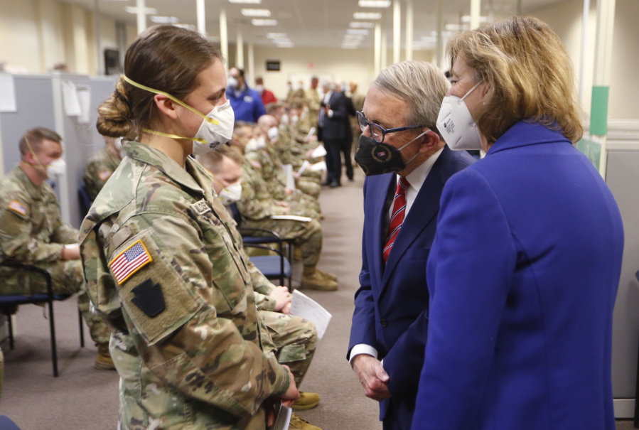 FILE - Ohio Gov. Mike DeWine, center, and his wife Fran, right, talk with specialist Emily Milosevic as they tour the Defense Supply Center Columbus in Columbus, Ohio, as members of the Ohio Army National Guard prepare to deploy to aid Ohio hospitals during the current surge in COVID-19 hospitalizations Jan. 6, 2022. Up to 40,000 Army National Guard soldiers across the country - or about 13% of the force -- have not yet gotten the mandated COVID-19 vaccine, and as the deadline for shots looms, at least 14,000 of them have flatly refused and could be forced out of the service.