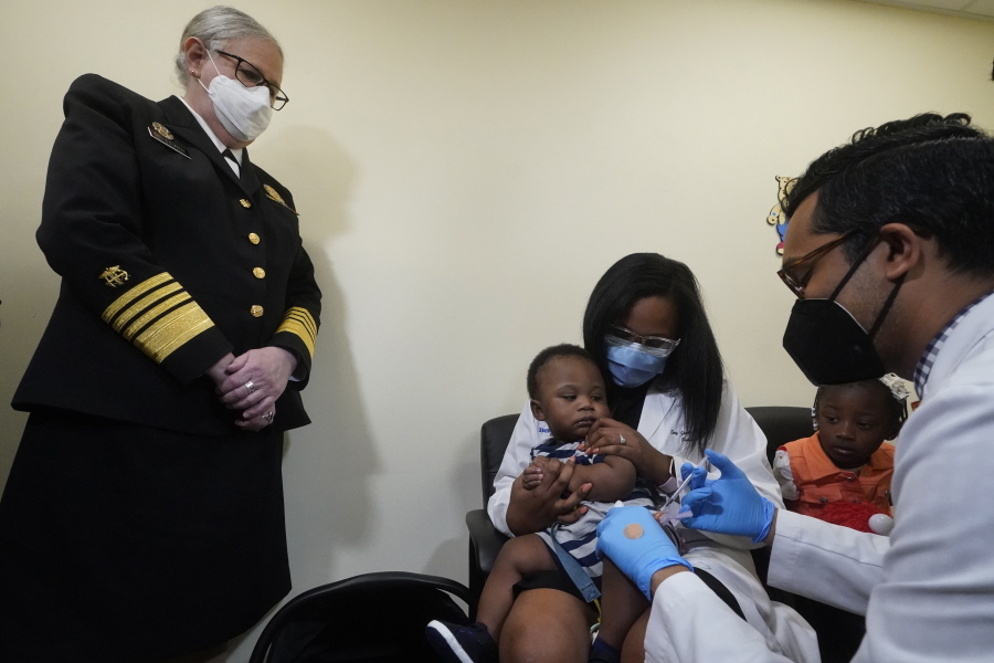 Pediatrician Emy Jean-Marie, center, holds her nine-month-old son Adedeji Adebayo, Emiola Adebayo, 3, on her lap as Dr. Nizar Dowla, right, administers a vaccine while       Department of Health and Human Services Assistant Secretary for Health, Admiral Rachel Levine, left, looks on, Tuesday, June 28, 2022, at the Borinquen Health Care Center in Miami. Florida is the only state that didn't pre-order the under-5 vaccine, and state Surgeon General Joseph Ladapo has recommended against vaccinating healthy children.