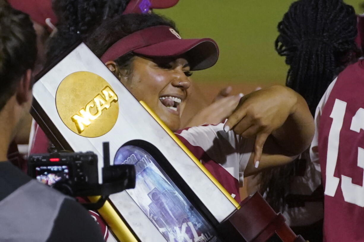 Oklahoma players celebrate with the trophy after defeating Texas in the NCAA softball Women's College World Series finals Thursday, June 9, 2022, in Oklahoma City.