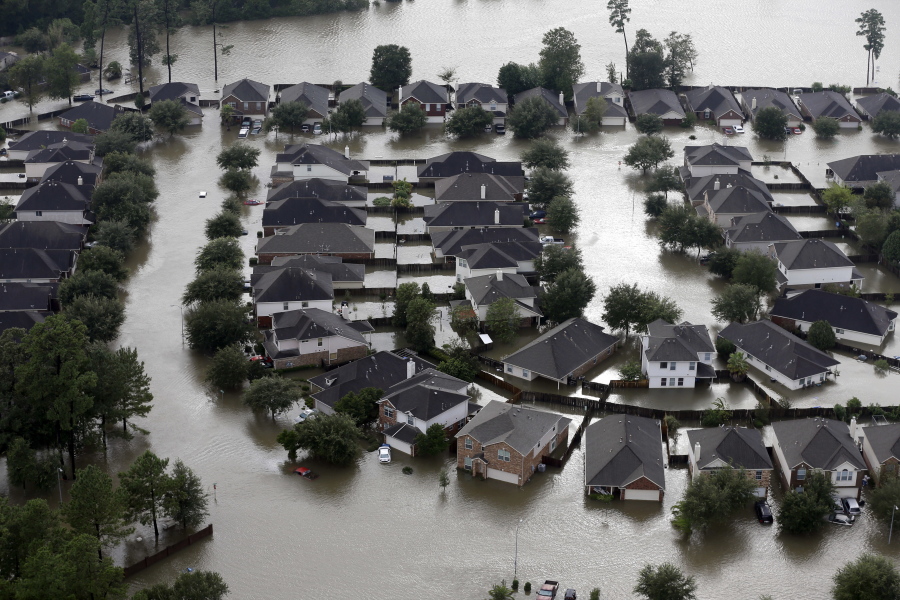 FILE - Homes are surrounded by floodwaters from Tropical Storm Harvey in Spring, Texas, Tuesday, Aug. 29, 2017. Experts say more intense storms driven by climate change are boosting contamination risks for privately-owned drinking water wells. (AP Photo/David J.