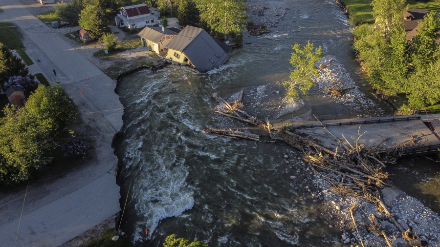 FILE - A house sits in Rock Creek after floodwaters washed away a road and a bridge in Red Lodge, Mont., on June 15, 2022. Yellowstone National Park is reopening its flood-damaged north loop at noon on Saturday, July 2, 2022, in time for the Fourth of July holiday weekend. Park officials say the roads from Norris Junction to Mammoth Hot Springs, to Tower-Roosevelt, to Canyon Junction and back to Norris Junction will be open. The loop is reopening nearly three weeks after massive flooding forced thousands to flee the park as water, rocks and mud washed out bridges and roads.