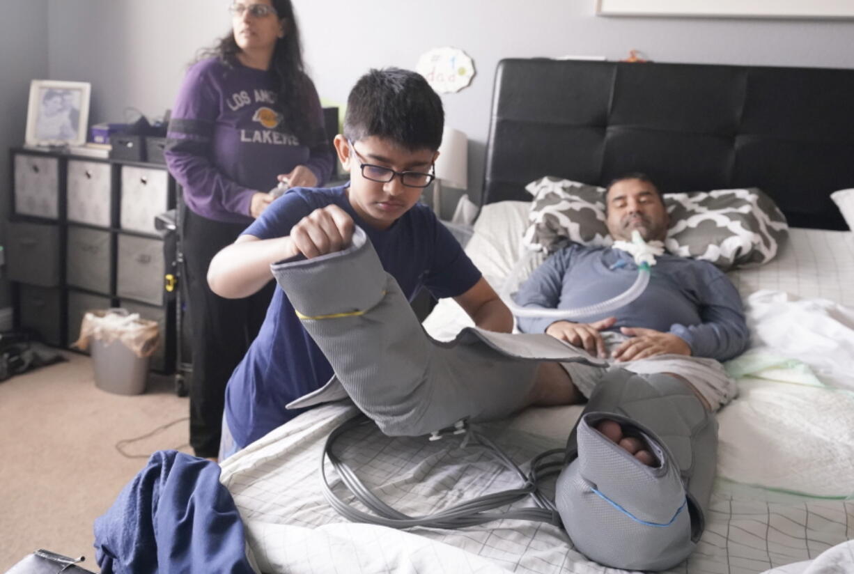 Ronan Kotiya, 11, removes a compression leg sleeve from his father Rupesh Kotiya as his mother Siobhan Pandya looks at their home in Plano, Texas, Sunday, April 10, 2022. Ronan helps care for his father who suffers from ALS and is dependent on a ventilator and around the clock care. Millions of Americans with serious health problems depend on children ages 18 and younger to provide some or all of their care at home. An exact number is hard to pin down, but researchers think millions of children are involved in caregiving in the U.S. Ronan helps care for his father who suffers from ALS and is dependent on a ventilator and around the clock care. Millions of Americans with serious health problems depend on children ages 18 and younger to provide some or all of their care at home. An exact number is hard to pin down, but researchers think millions of children are involved in caregiving in the U.S.