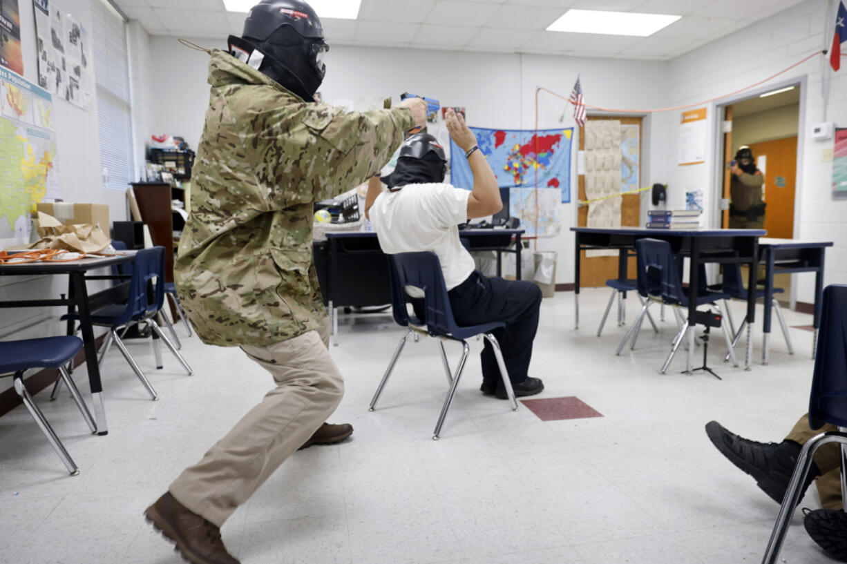 Advanced Law Enforcement Rapid Response Training instructor Troy Dupuy, acting as an active shooter, trades gunfire with Texas DPS Trooper Chuck Pryor (in doorway) during a Simunition training scenario inside an Athens Sr. High School classroom, in Athens, Texas, June 21, 2022. The shooters use handguns that fire soap-based marking cartridges to simulate gunfire.