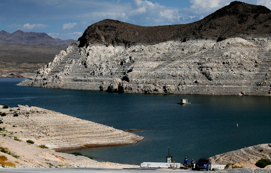 Kayakers taking their gear out of the water are dwarfed by a white bathtub ring around Echo Bay in Lake Mead.