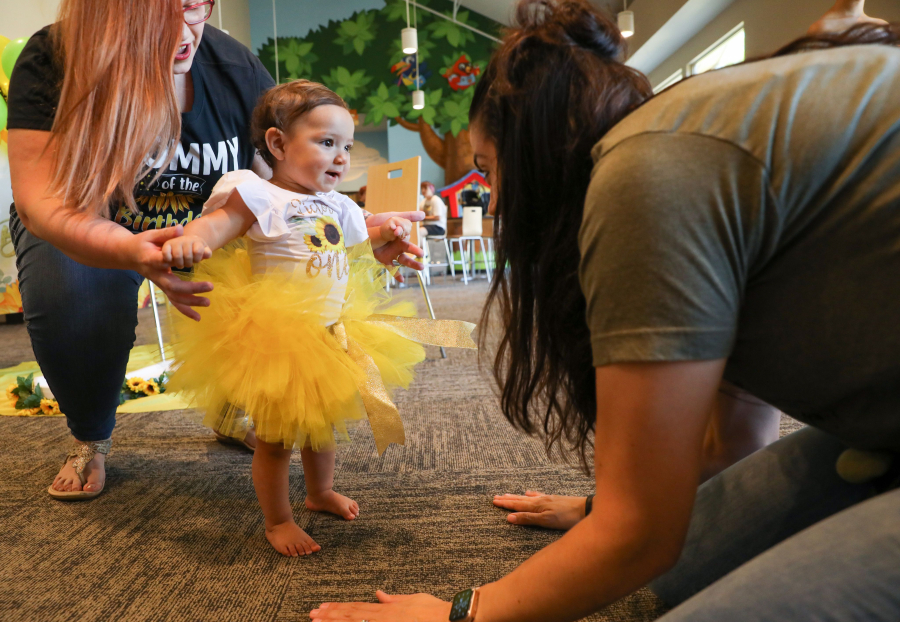 Blue Haven Ranch chairman Brittany White, right, sings and acts out "The Ants Go Marching," with Victoria Gwynn, 1, and her mother Gabbie Gwynn, left, at Victoria's first birthday party July 11 at Oak Hills Community Church in Argyle, Texas.